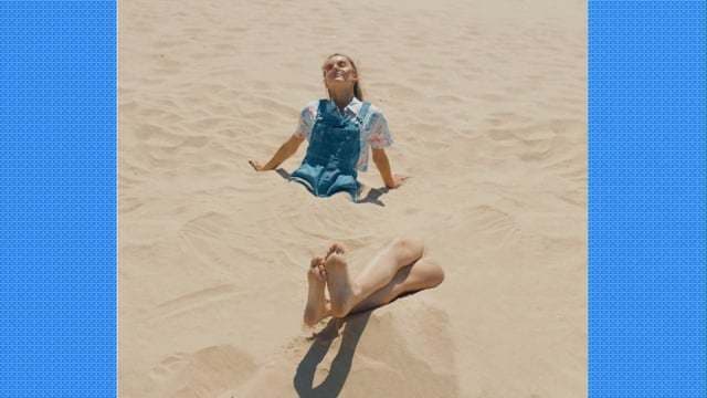a woman laying on top of a sandy beach