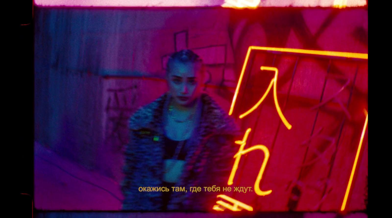 a woman standing in front of a neon sign