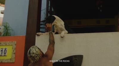 a man holding a surfboard next to a dog