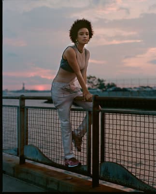 a woman leaning on a rail next to a body of water
