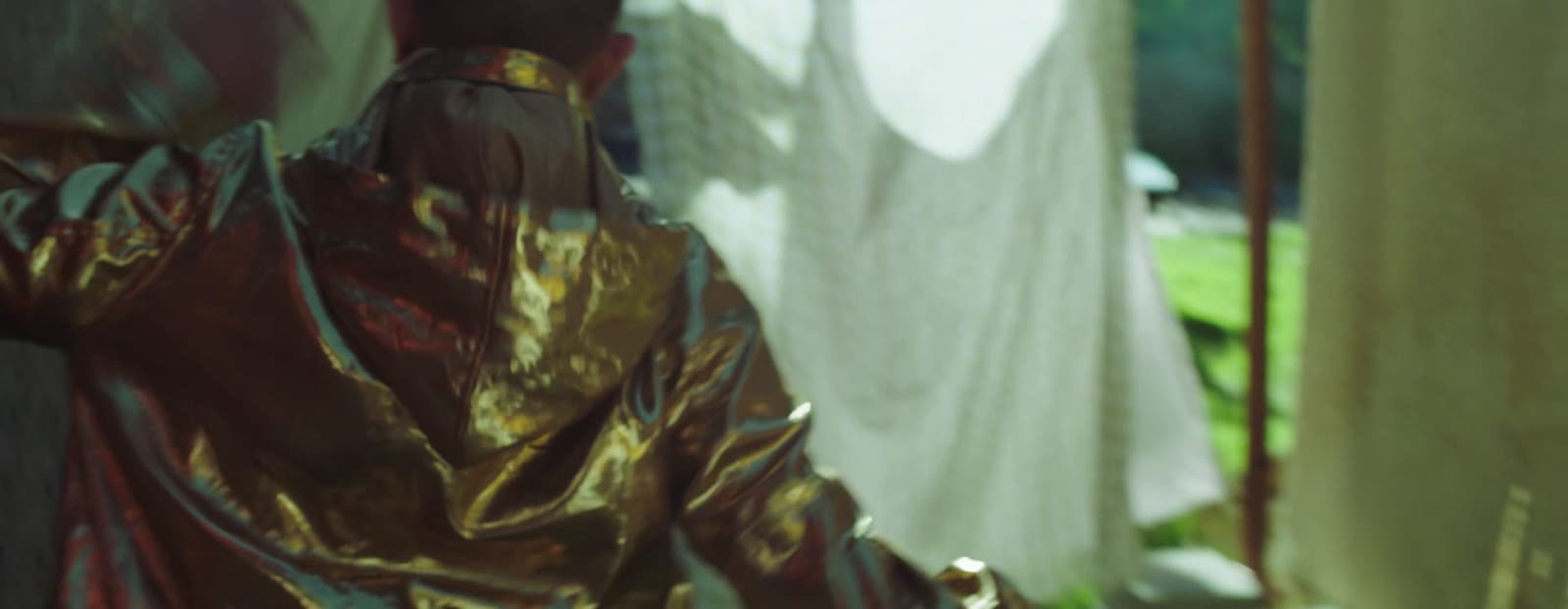 a person in a shiny gold outfit sitting on a bench