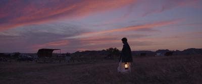 a person standing in a field at sunset