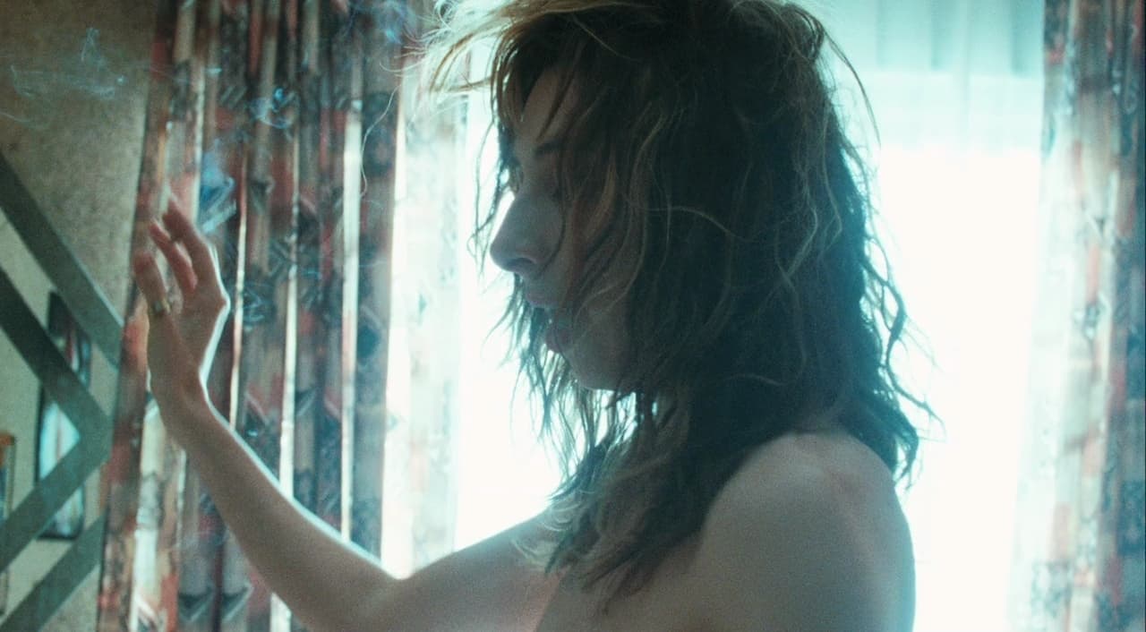 a shirtless woman standing in front of a window