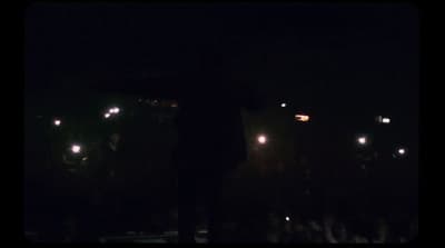 a man standing in front of a crowd at night