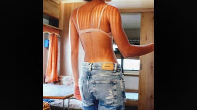 a woman in a white bra top and ripped jeans