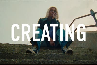 a woman sitting on steps with the words creating in front of her