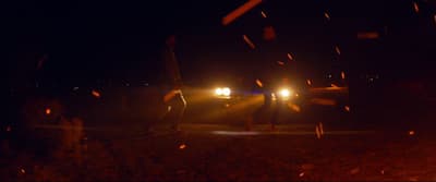 a couple of people standing next to a car at night