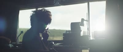 a man sitting in front of a window talking on a cell phone