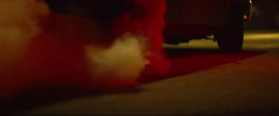 a red teddy bear sitting on the ground next to a car