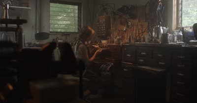 a woman sitting in a room with lots of clutter