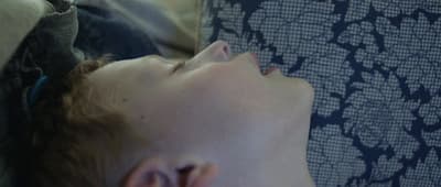 a young man sleeping on a couch with his eyes closed