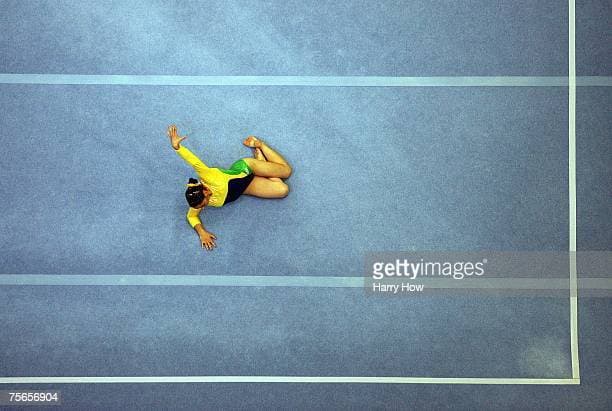 a woman on a blue tennis court with her hands in the air