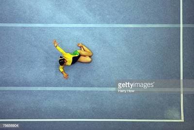 a woman on a blue tennis court with her hands in the air