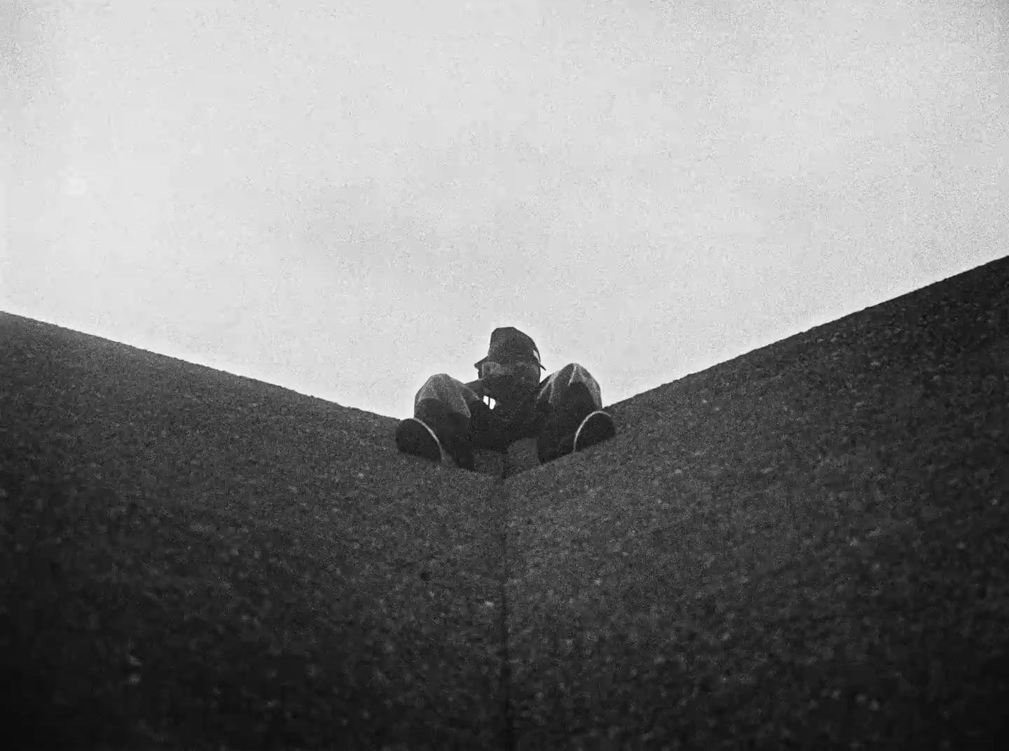 a man sitting on top of a roof next to a skateboard