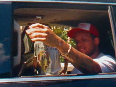 a man in a red hat is holding something out of a car window