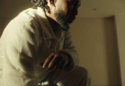 a man with curly hair and a beard sitting down