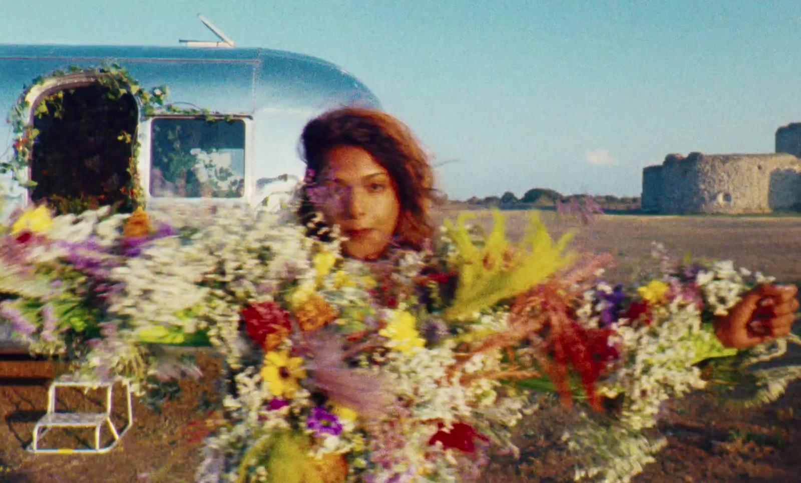 a woman holding a bouquet of flowers in front of a trailer