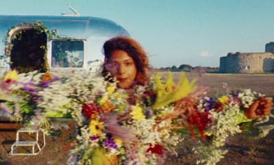 a woman holding a bouquet of flowers in front of a trailer
