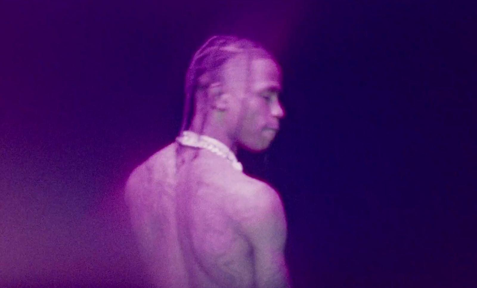 a man with long hair standing in a dark room