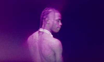 a man with long hair standing in a dark room