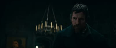 a man standing in a dark room with a chandelier