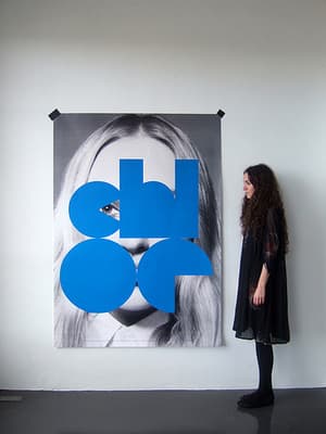a woman standing in front of a poster of a woman's face