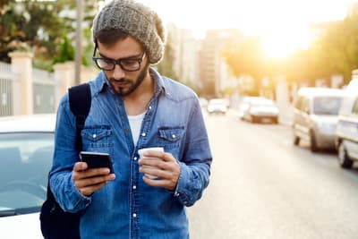 a man standing on a street looking at his cell phone