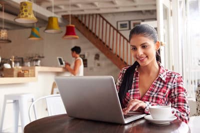 a woman sitting at a table using a laptop computer