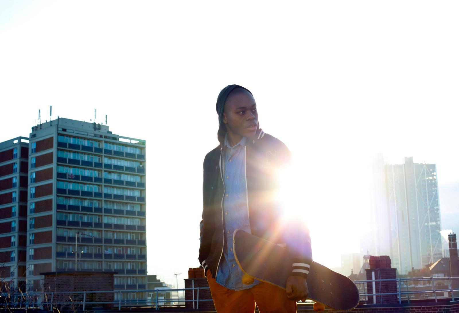a woman holding a skateboard in front of a city skyline