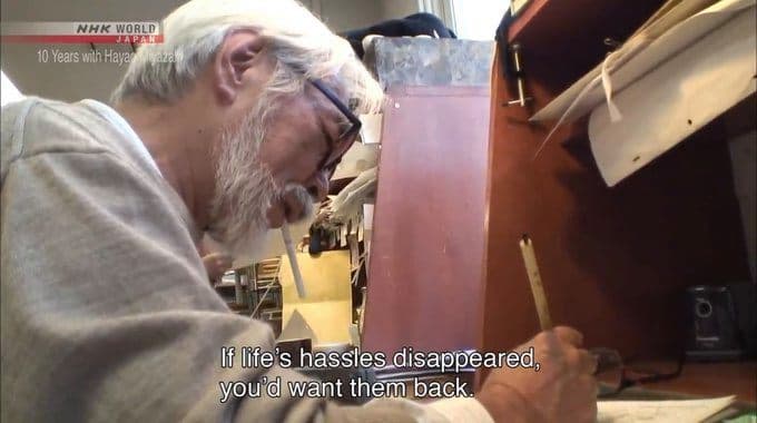 a man with a beard and glasses working on a piece of wood