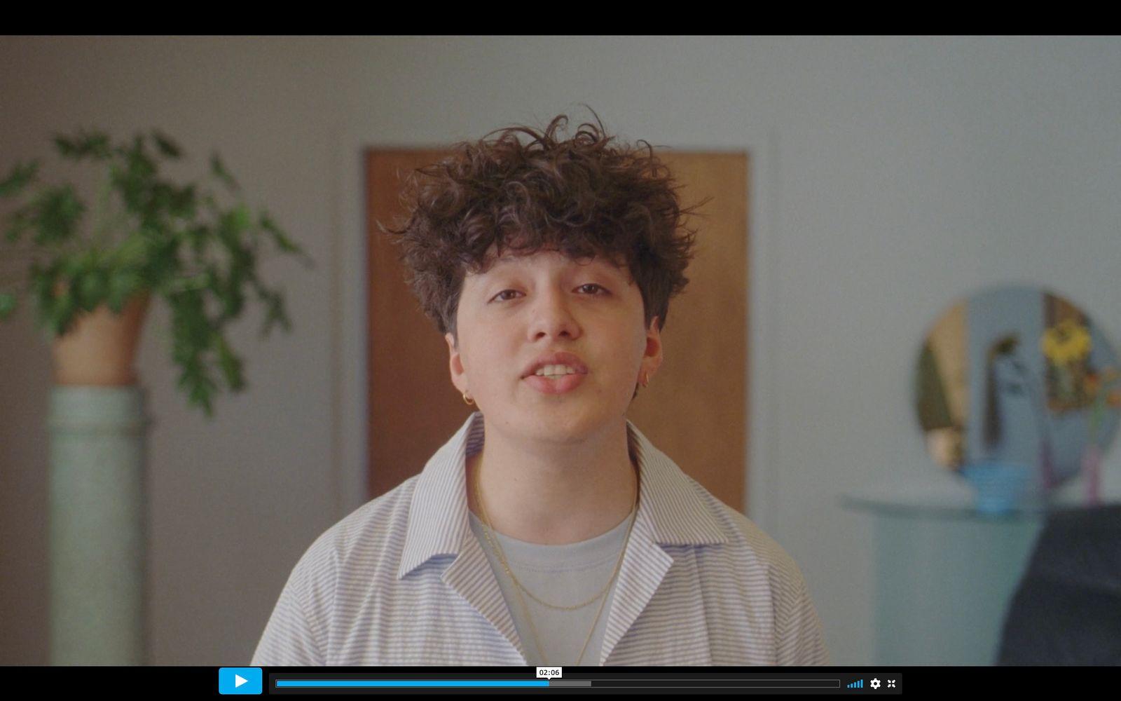 a man with curly hair standing in a room