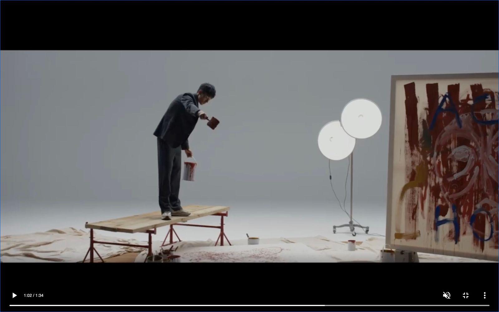a man standing on top of a table next to a painting