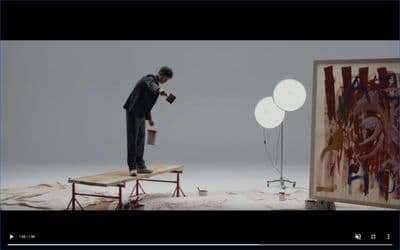 a man standing on top of a table next to a painting