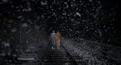 two people walking down a train track in the rain