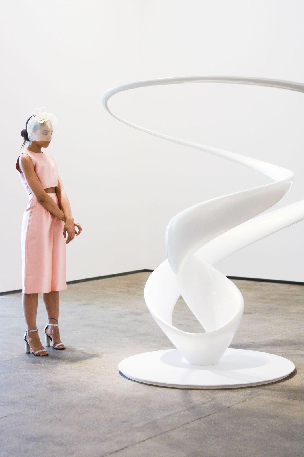 a woman standing in front of a white sculpture