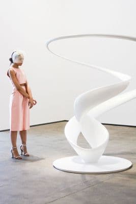 a woman standing in front of a white sculpture