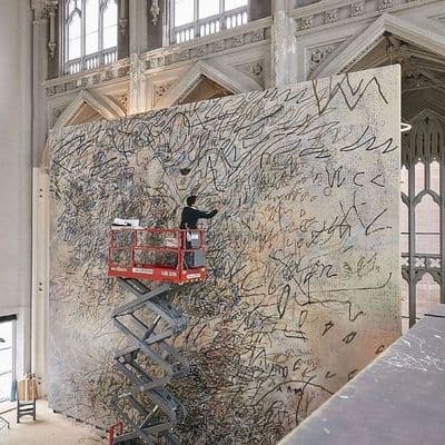 a man is painting a large wall with graffiti