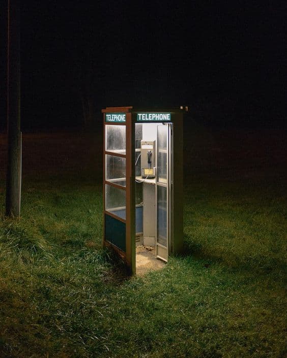 a phone booth sitting in the middle of a field