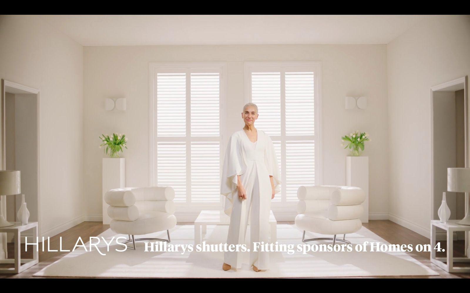 a woman standing in a living room with white furniture