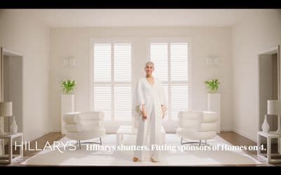 a woman standing in a living room with white furniture