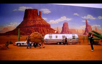 a painting of a desert scene with people and vehicles