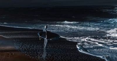 a person standing on a beach holding a surfboard