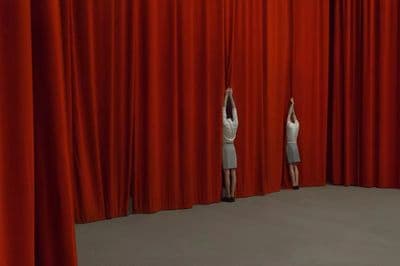 a woman standing on a stage in front of a red curtain