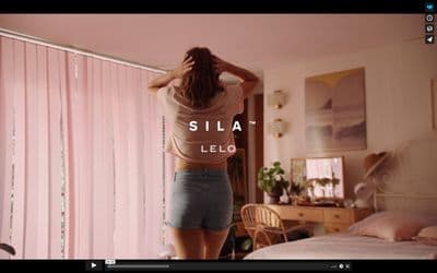 a woman standing in front of a bed in a bedroom
