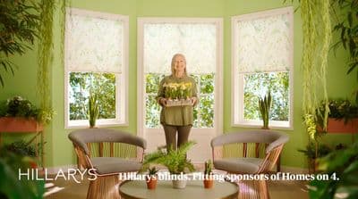 a woman standing in a living room holding a tray of flowers