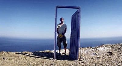 a man standing in front of a door on top of a mountain