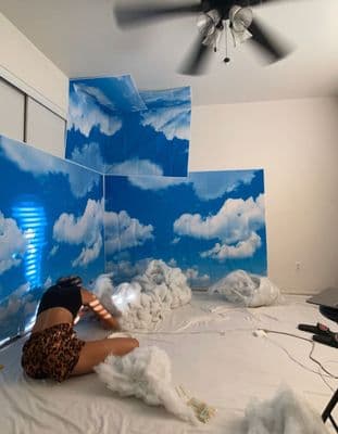 a woman laying on top of a bed covered in clouds