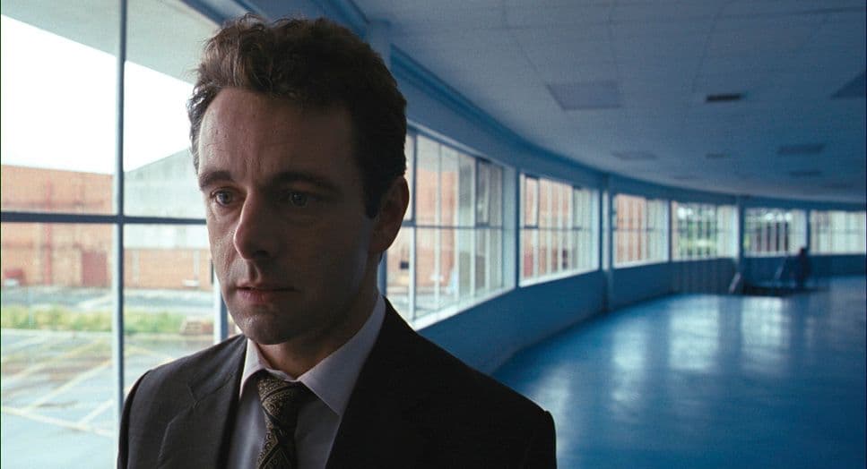a man in a suit and tie standing in front of a window