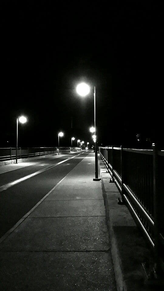 a black and white photo of a street at night