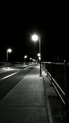 a black and white photo of a street at night